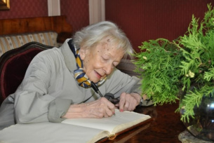 Wisława Szymborska wpisuje się do księgi pamiątkowej Muzeum